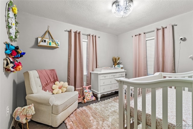 bedroom with a textured ceiling, multiple windows, and a crib