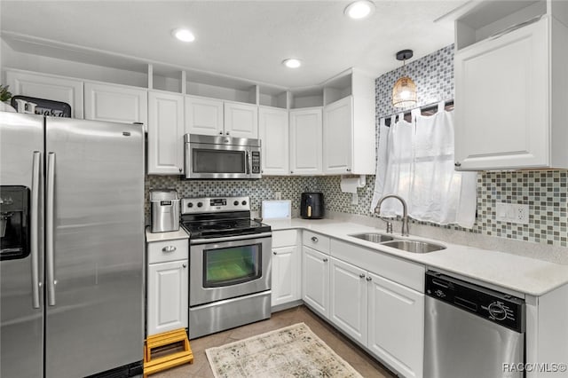 kitchen featuring backsplash, sink, hanging light fixtures, white cabinetry, and stainless steel appliances