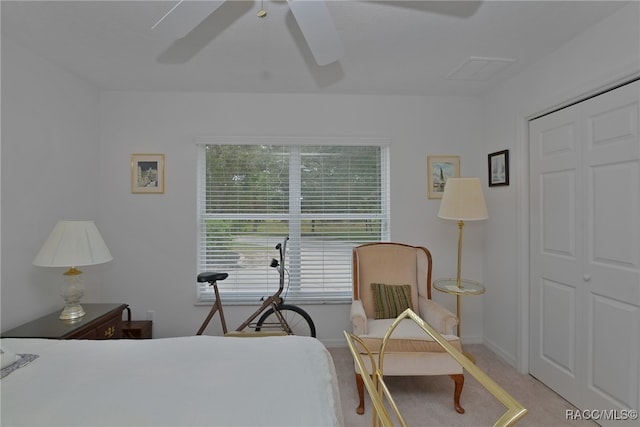 bedroom with ceiling fan, light carpet, and a closet