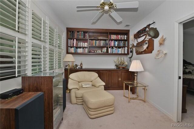 living area with light colored carpet and ceiling fan