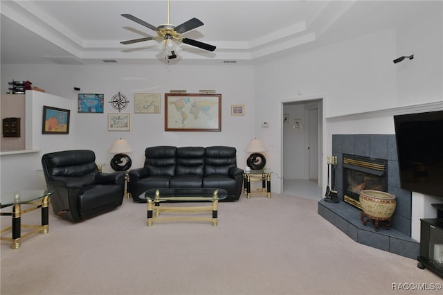 carpeted living room featuring ceiling fan, a fireplace, and a tray ceiling