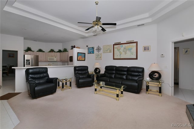 tiled living room featuring a tray ceiling and ceiling fan