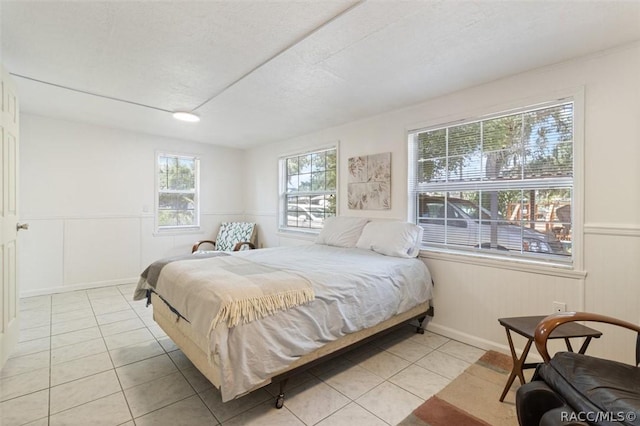 bedroom with multiple windows, light tile patterned floors, and a textured ceiling