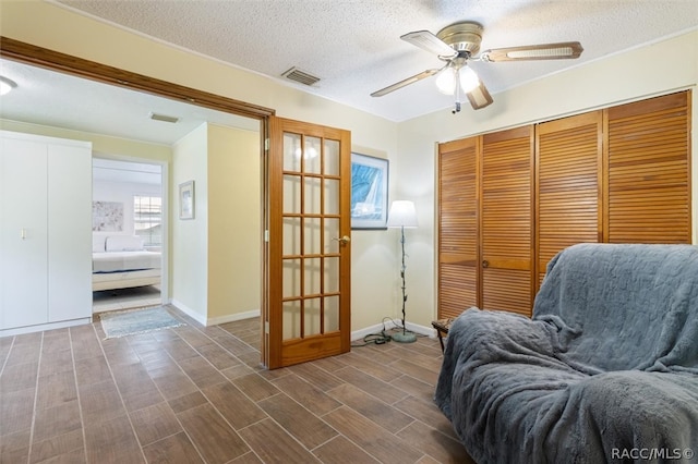 sitting room with ceiling fan, a textured ceiling, and french doors