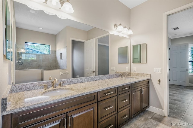 bathroom featuring tiled shower and vanity