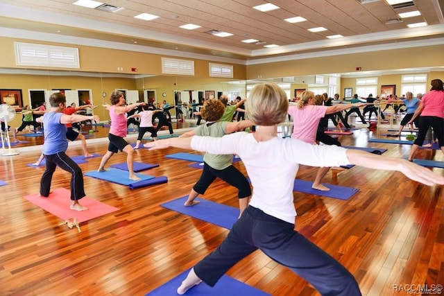 gym with light hardwood / wood-style floors and crown molding