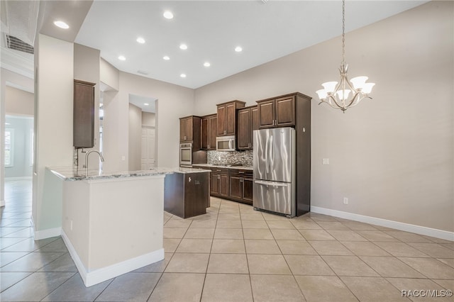 kitchen featuring stainless steel appliances, hanging light fixtures, light stone counters, decorative backsplash, and light tile patterned flooring