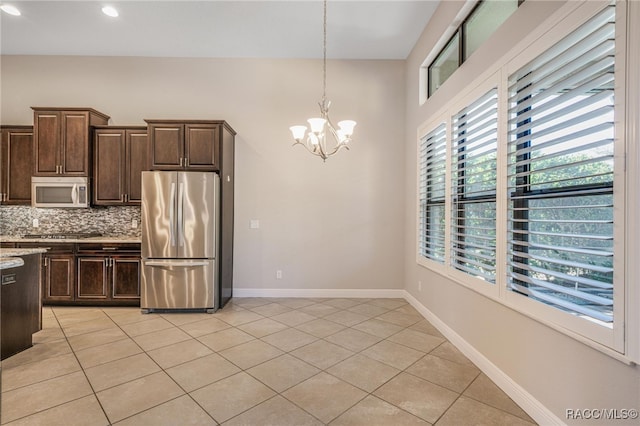 kitchen with hanging light fixtures, stainless steel appliances, light tile patterned floors, decorative backsplash, and an inviting chandelier