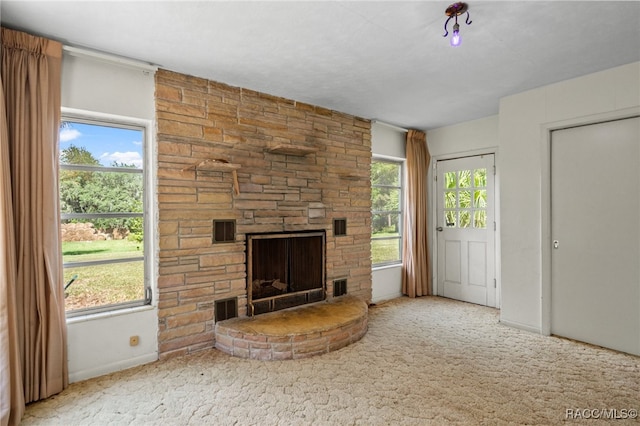 unfurnished living room with carpet flooring and a stone fireplace