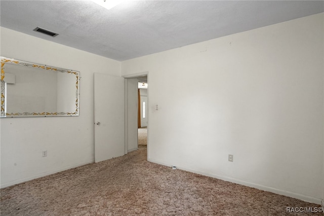 carpeted empty room with a textured ceiling