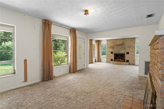 unfurnished living room featuring carpet flooring, a fireplace, and a healthy amount of sunlight