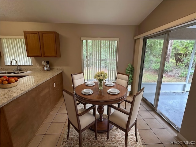 dining room featuring plenty of natural light, light tile patterned flooring, and lofted ceiling