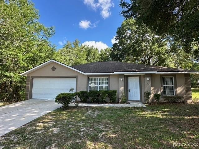 ranch-style house featuring an attached garage, concrete driveway, stucco siding, and a front yard