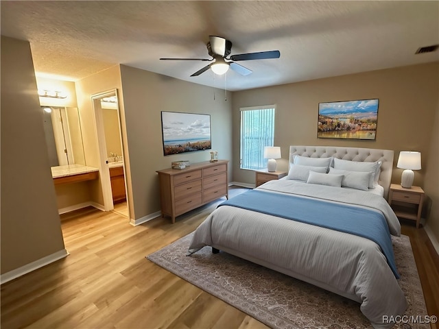 bedroom with light wood-style floors, baseboards, connected bathroom, and a ceiling fan