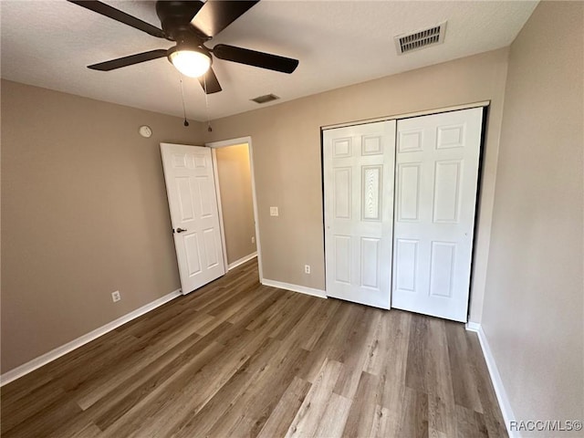 unfurnished bedroom featuring wood finished floors, baseboards, a closet, and ceiling fan