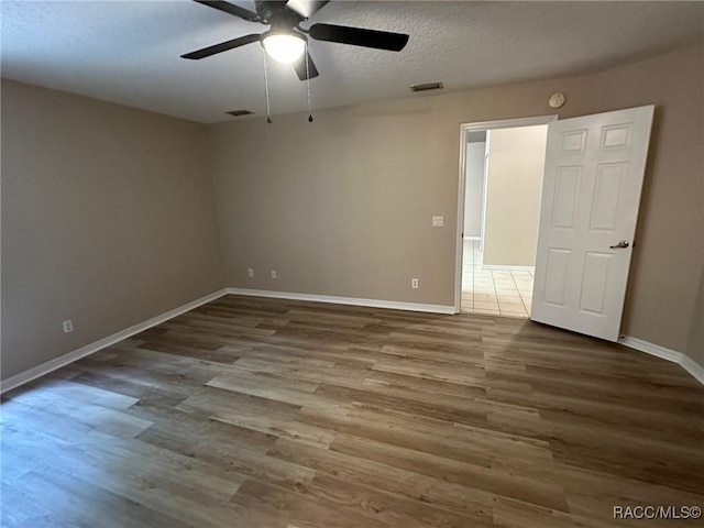spare room featuring ceiling fan, wood finished floors, baseboards, and a textured ceiling