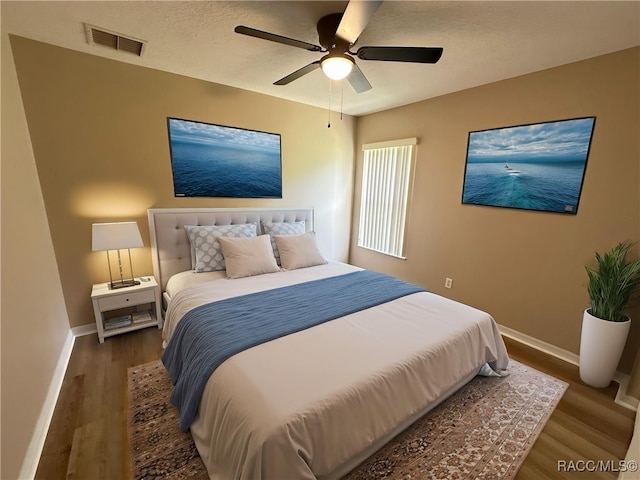 bedroom with baseboards, wood finished floors, ceiling fan, and a textured ceiling