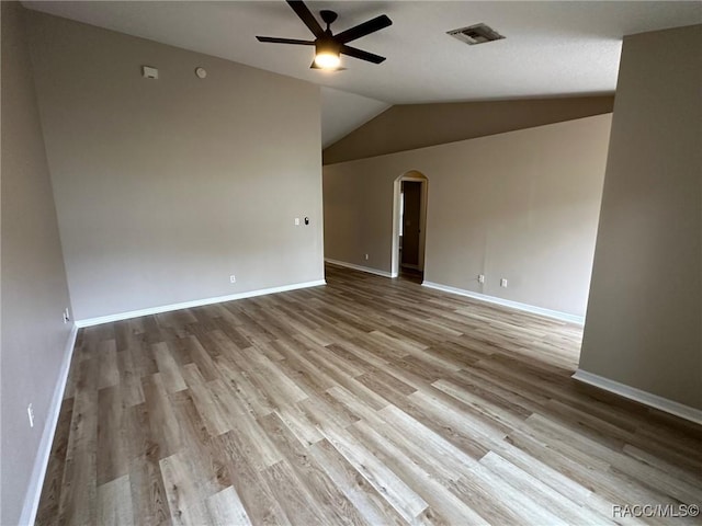 unfurnished room with a ceiling fan, arched walkways, wood finished floors, baseboards, and lofted ceiling