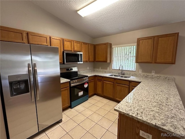kitchen featuring appliances with stainless steel finishes, a sink, brown cabinets, lofted ceiling, and a textured ceiling
