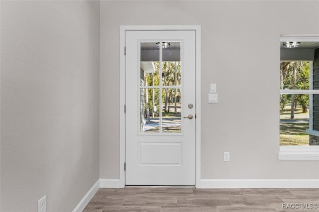 doorway to outside featuring a healthy amount of sunlight, baseboards, and wood finished floors