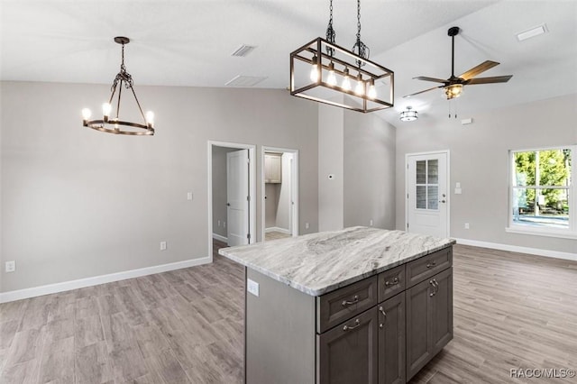 kitchen featuring ceiling fan with notable chandelier, a kitchen island, baseboards, open floor plan, and light wood-style floors