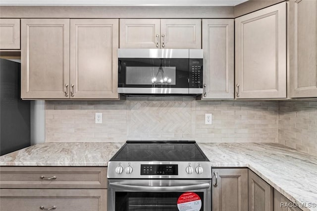 kitchen with light stone countertops, appliances with stainless steel finishes, and backsplash