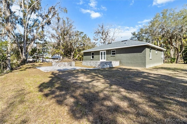 rear view of property with a yard and stucco siding