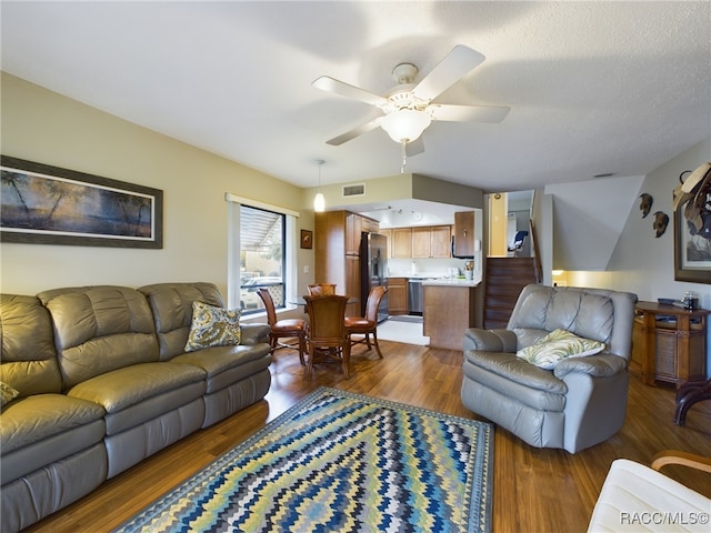 living room featuring a textured ceiling, dark hardwood / wood-style flooring, and ceiling fan