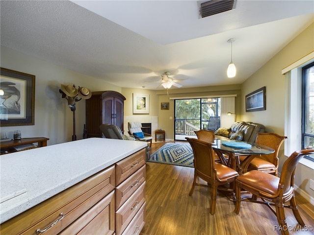 kitchen with dark hardwood / wood-style flooring, decorative light fixtures, ceiling fan, and a tiled fireplace