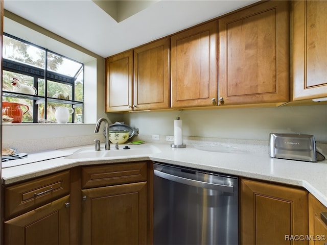 kitchen featuring stainless steel dishwasher, light stone countertops, and sink