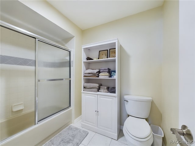 bathroom featuring tile patterned floors, toilet, and enclosed tub / shower combo