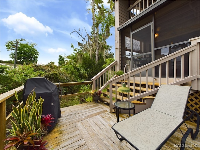 wooden terrace featuring a grill and a sunroom