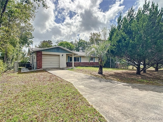 ranch-style house featuring central air condition unit, concrete driveway, a front yard, a garage, and brick siding