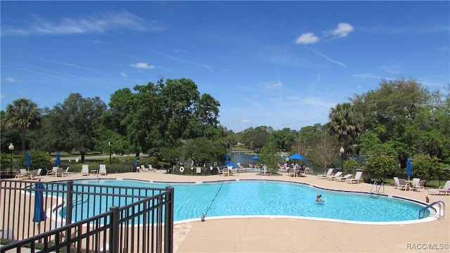 community pool with a patio and fence