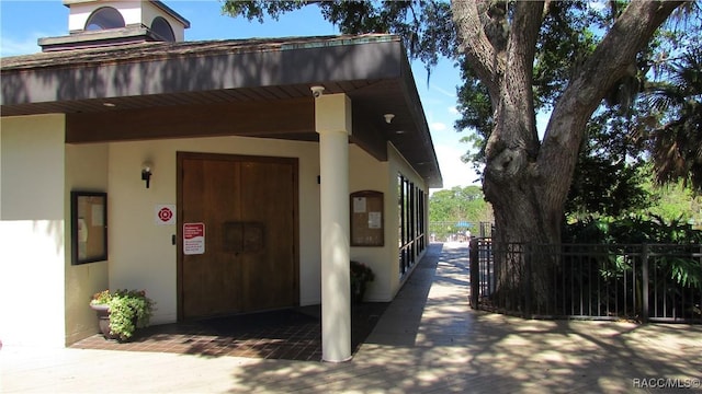 entrance to property with fence and stucco siding