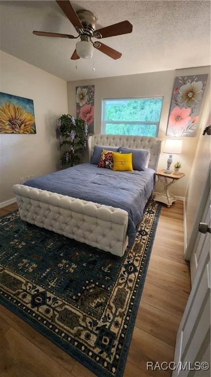 bedroom featuring a textured ceiling, light wood-type flooring, and ceiling fan