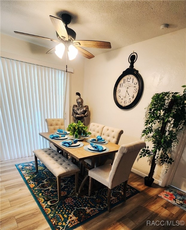 dining room featuring ceiling fan, wood-type flooring, and a textured ceiling