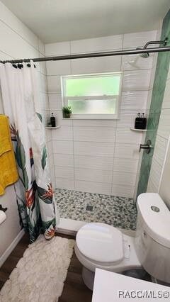 bathroom with a shower with shower curtain and toilet