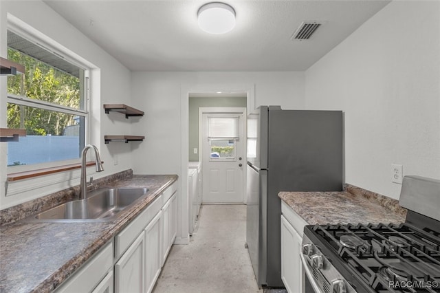 kitchen with appliances with stainless steel finishes, plenty of natural light, white cabinets, and independent washer and dryer