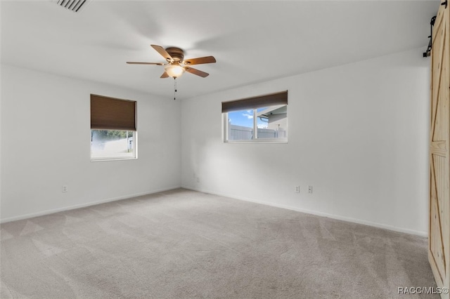 unfurnished room with a wealth of natural light, ceiling fan, and light carpet