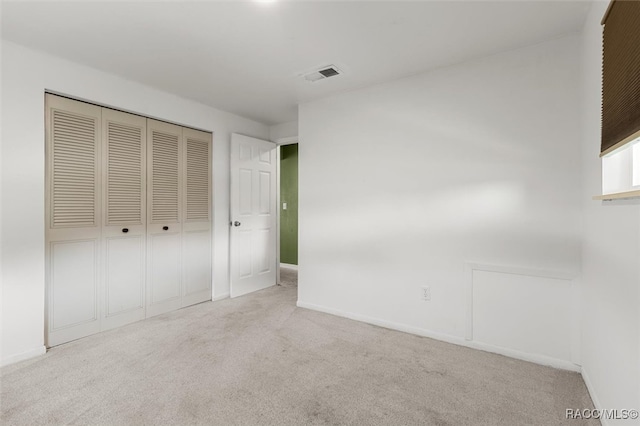 unfurnished bedroom with light carpet and a closet