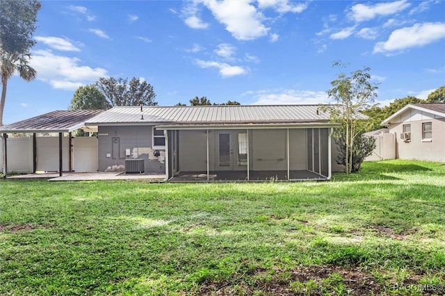 rear view of property featuring a patio area, a sunroom, a yard, and central AC