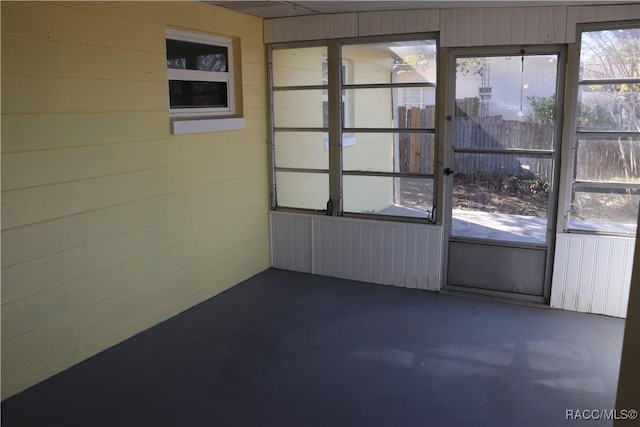 unfurnished room featuring wooden walls