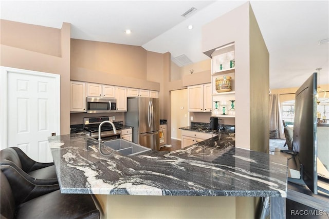 kitchen with dark stone countertops, sink, kitchen peninsula, and stainless steel appliances