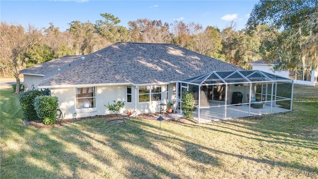 rear view of house with a patio, glass enclosure, and a lawn