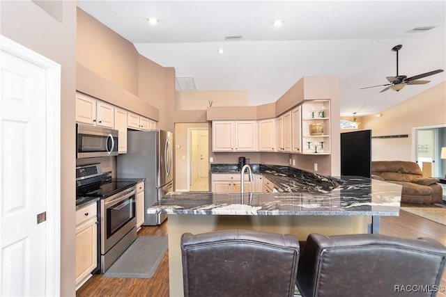 kitchen featuring lofted ceiling, ceiling fan, appliances with stainless steel finishes, dark hardwood / wood-style flooring, and a breakfast bar area