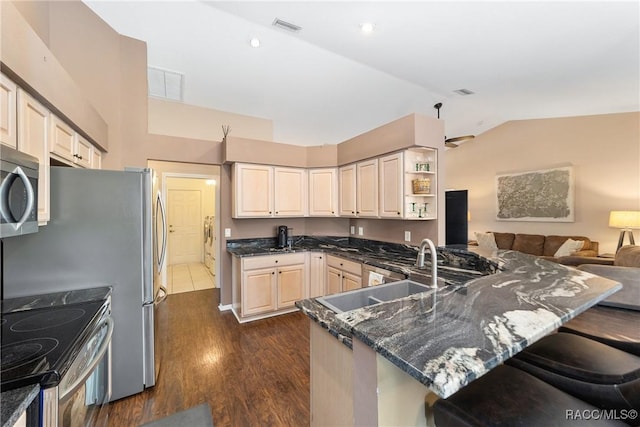 kitchen featuring kitchen peninsula, sink, appliances with stainless steel finishes, and vaulted ceiling