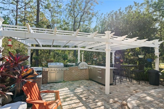 view of patio / terrace featuring a bar, a pergola, area for grilling, and exterior kitchen