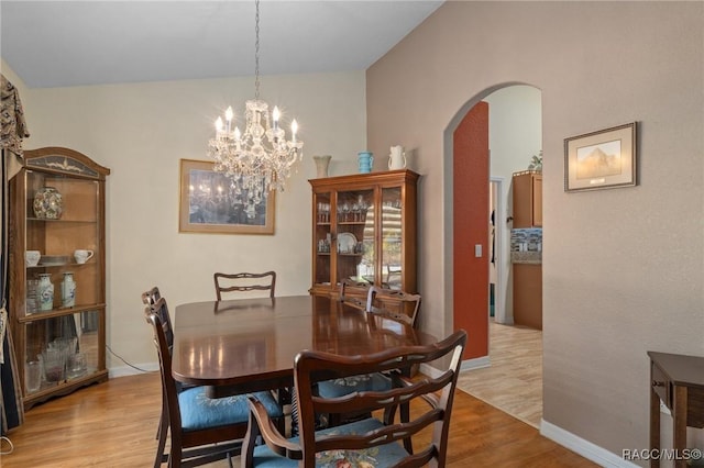 dining room with vaulted ceiling, an inviting chandelier, and light hardwood / wood-style flooring