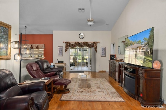 living room with ceiling fan, light hardwood / wood-style floors, and high vaulted ceiling